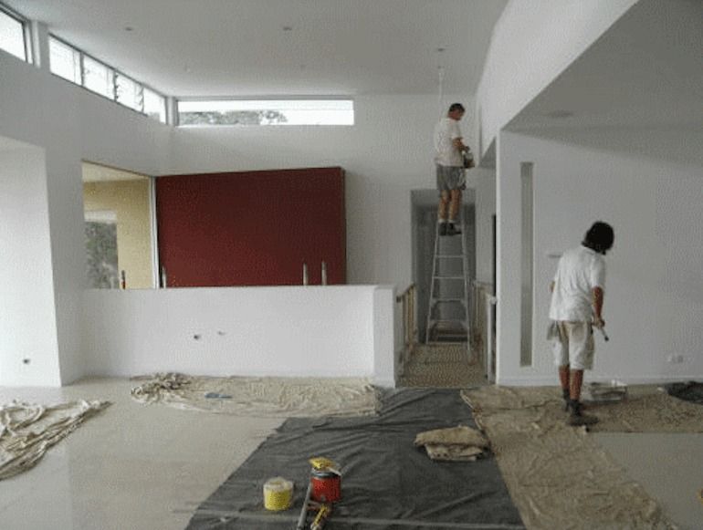 Two Men Are Painting A Wall In An Empty Room — Yves De Wilde Quality Painting Services In Lismore, NSW