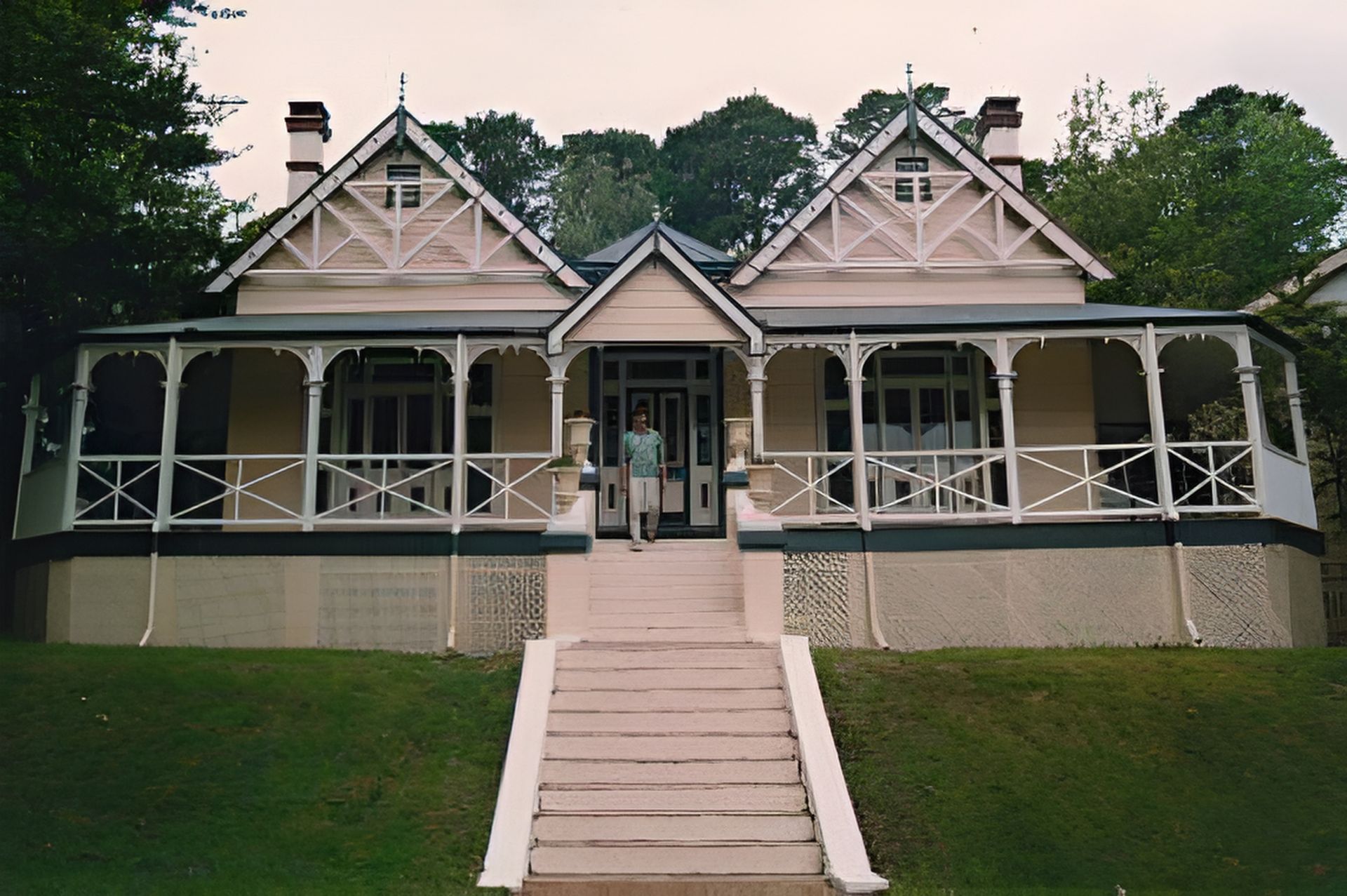 A Man Stands In Front Of A Large House With Stairs Leading Up To It — Yves De Wilde Quality Painting Services In Lismore, NSW