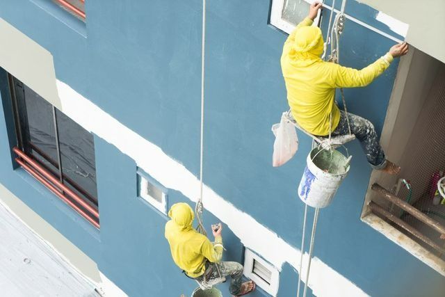 Two Men Are Painting A Building From A Rope — Yves De Wilde Quality Painting Services In Lismore, NSW