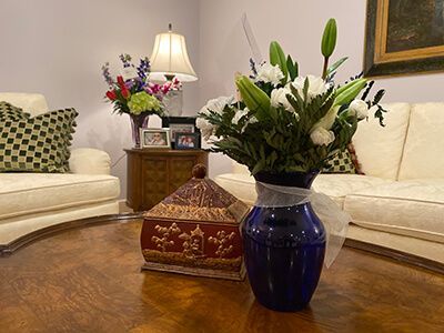 Living room with white sofas, flowers in a blue vase, and a decorative box on a wooden coffee table