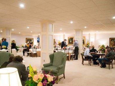 Spacious banquet hall with guests seated at tables and a green armchair in the foreground