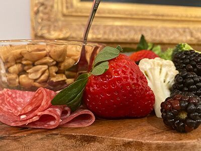 Charcuterie board with salami, almonds, strawberries, blackberries, and cream cheese with crackers