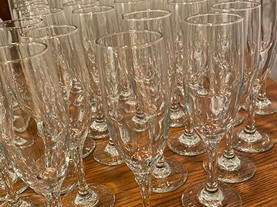 Rows of clear champagne flutes arranged on a wooden table