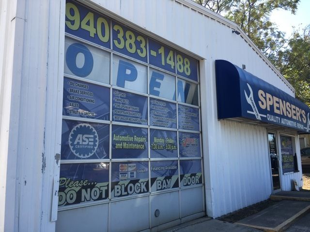 Auto repair shop exterior with blue garage door and open sign under the Spencer's Auto banner | Spenser's Quality Automotive