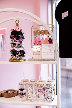 Pink shelf display with decorated tree, pastel gifts, and jars of treats in a shop window