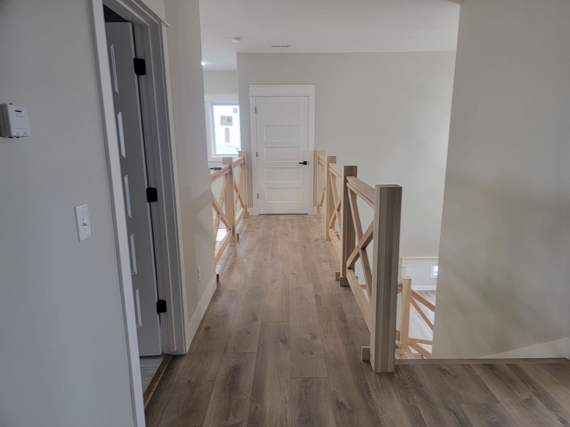 A hallway with wooden floors and stairs in a house.
