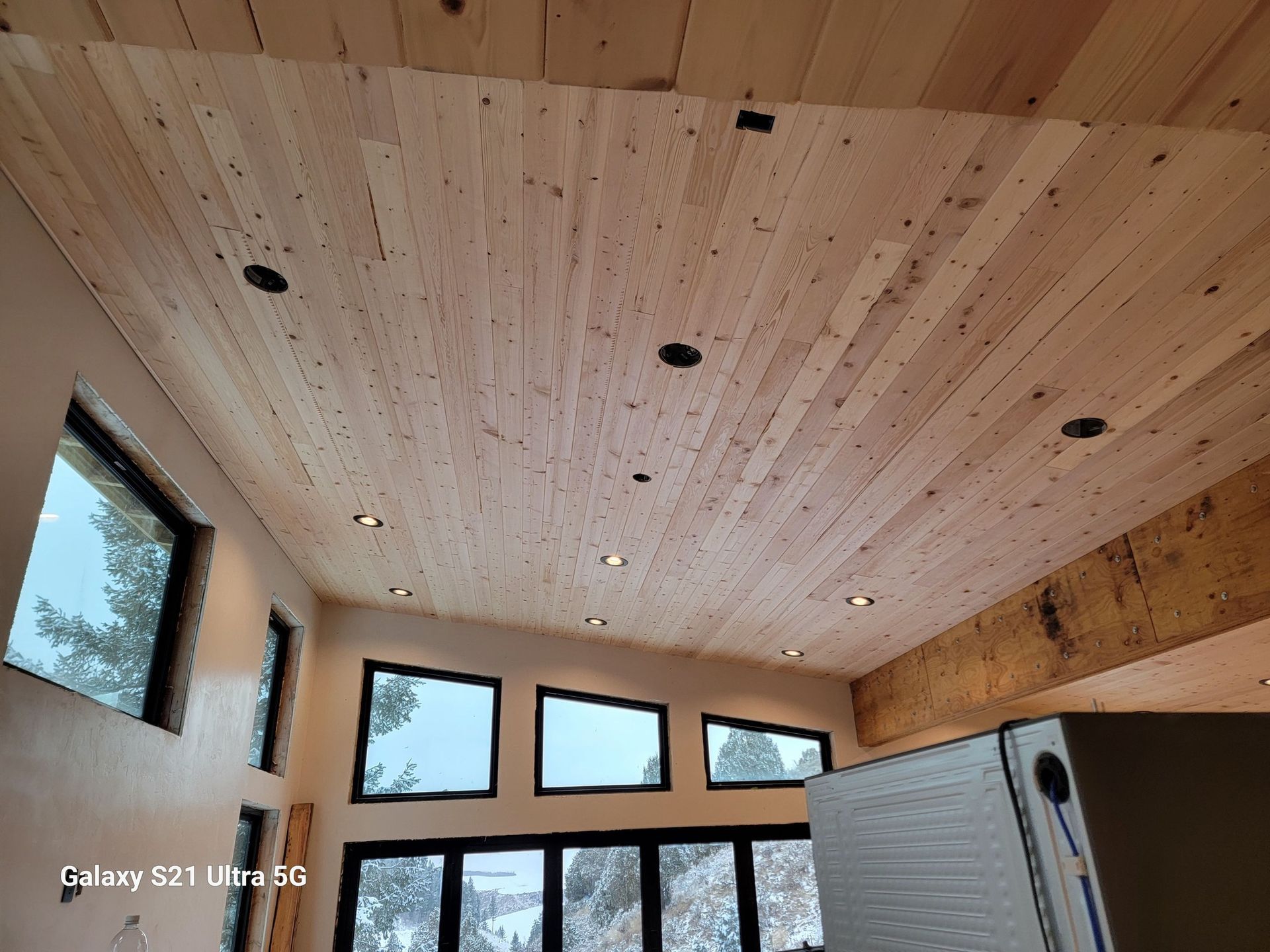 A room with a wooden ceiling and lots of windows.