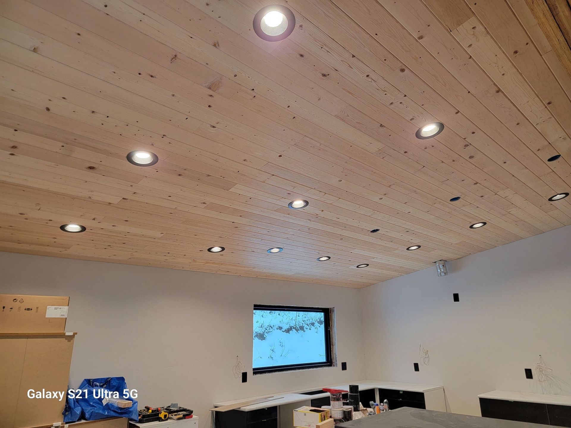 A living room with a wooden ceiling and a flat screen tv.