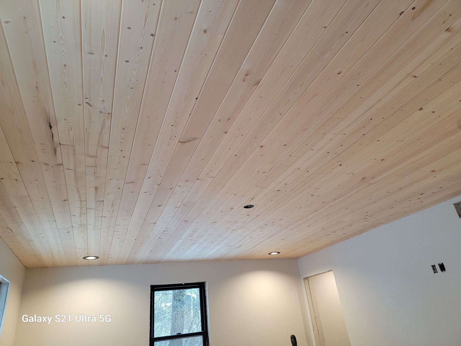 A room with a wooden ceiling and a window.