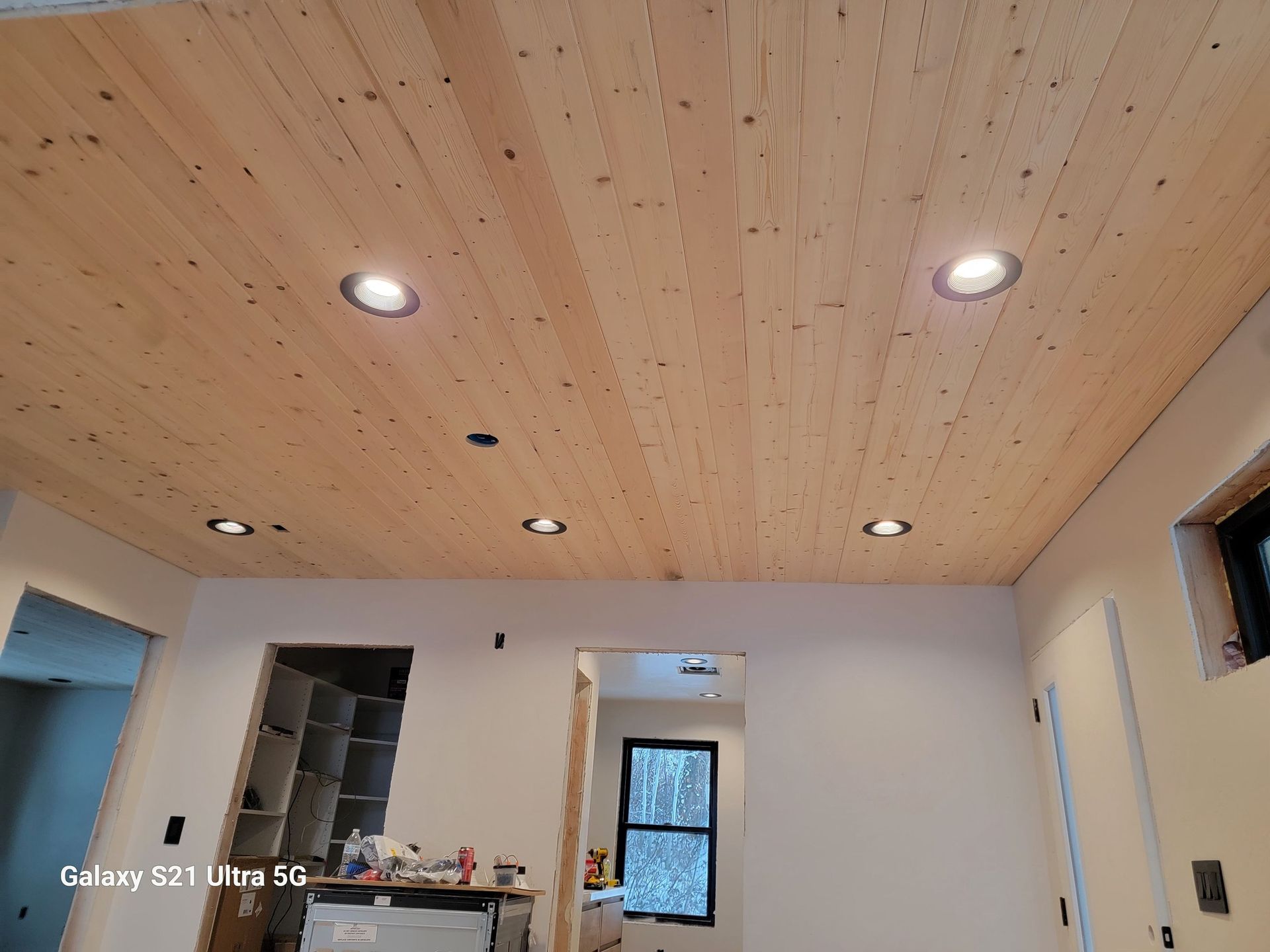 A room with a wooden ceiling and a galaxy s21 ultra 5g in the background.
