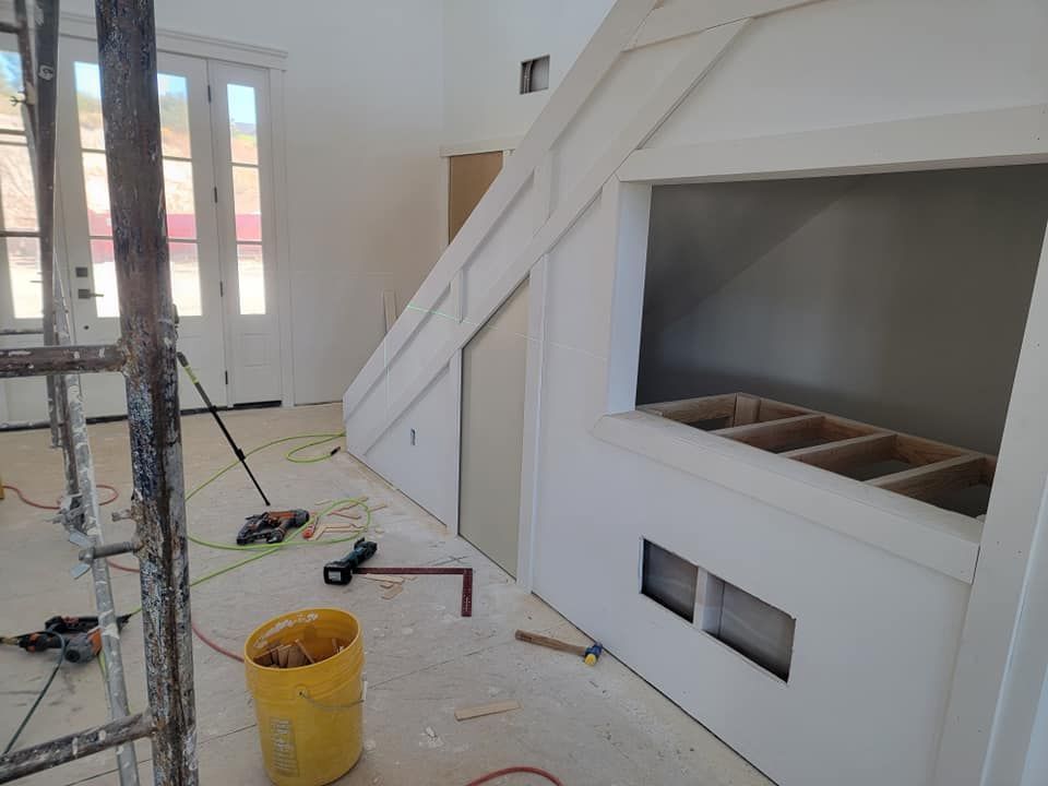 A yellow bucket is sitting on the floor in a room under construction.
