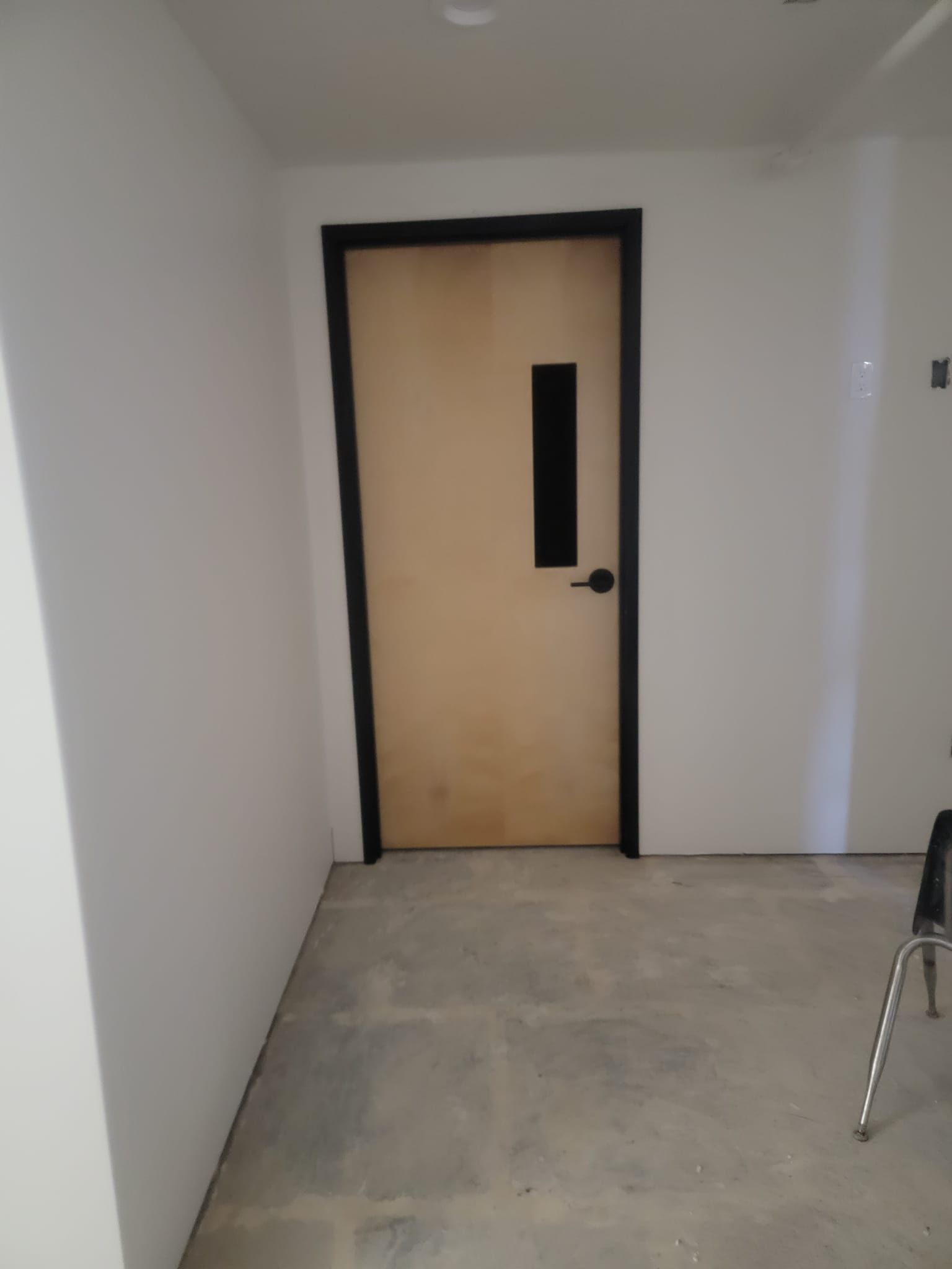 A hallway with a door and a chair in it