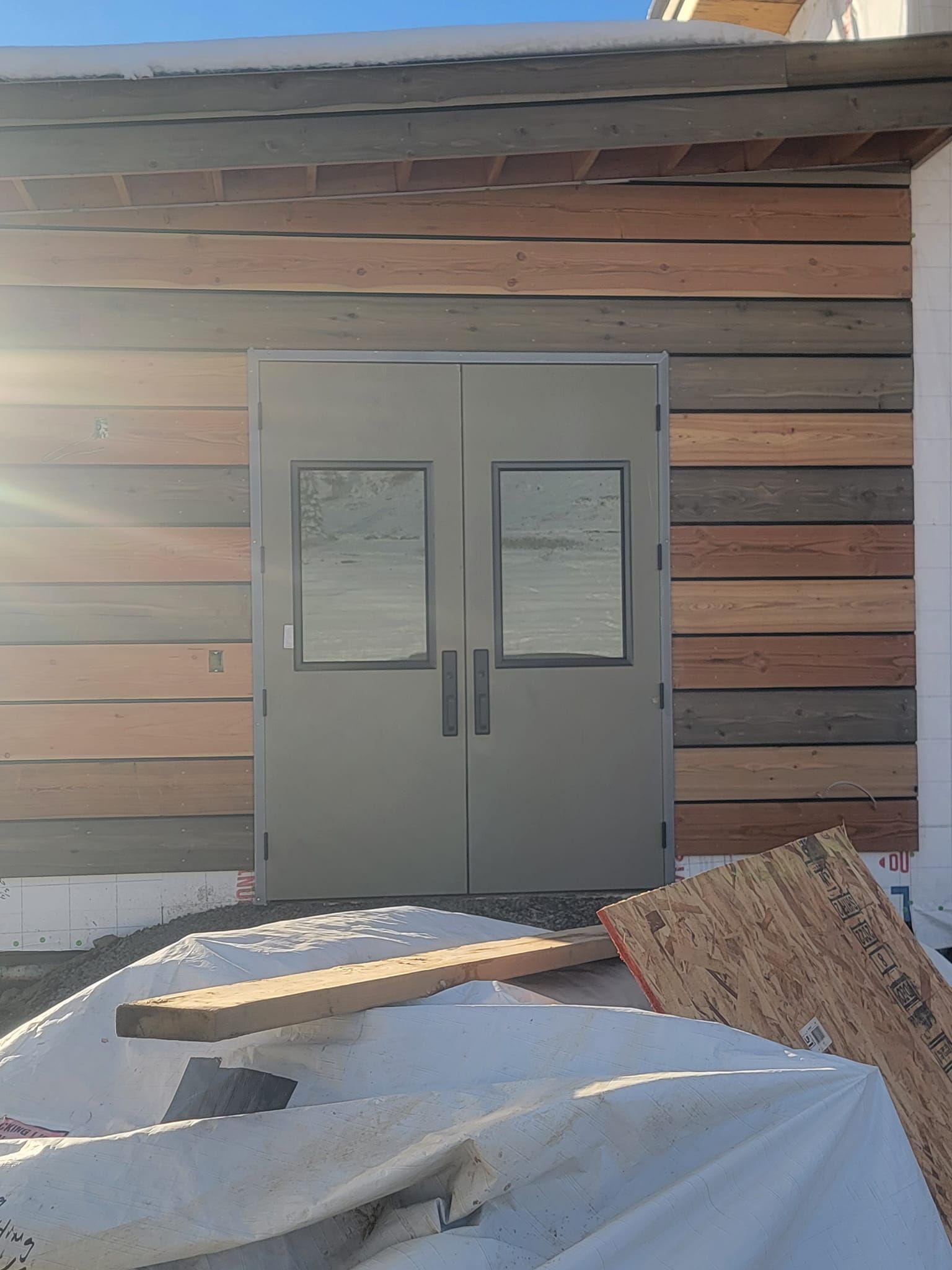 A building with a gray door and wooden siding