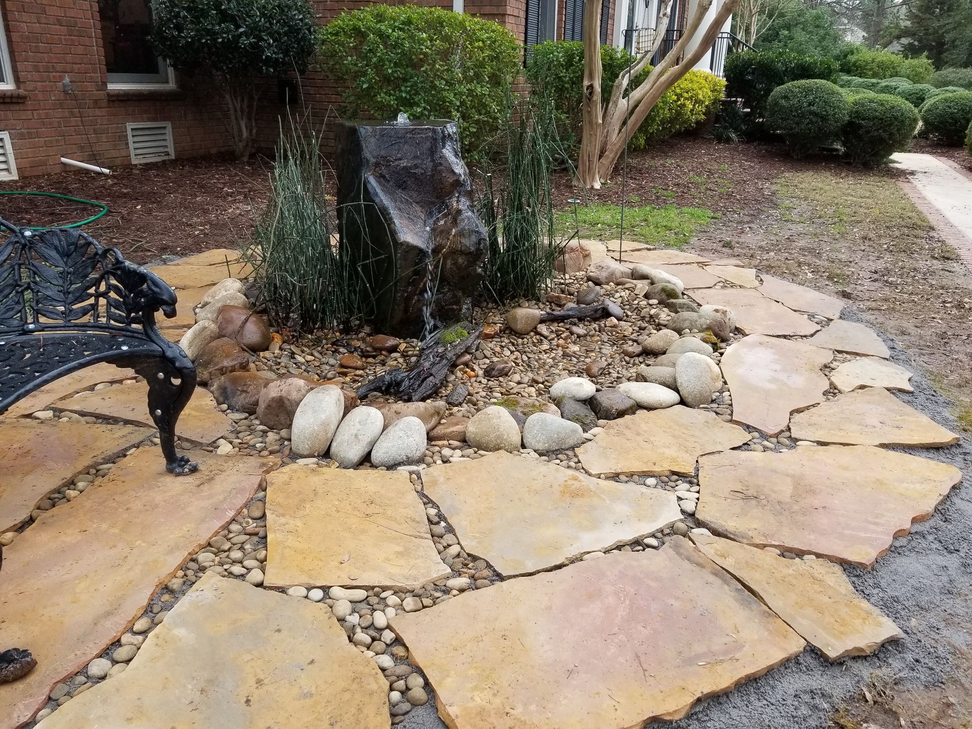 A stone walkway with a bench and a fountain in the middle.