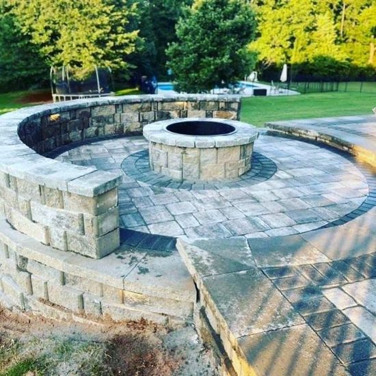 A fire pit is sitting on a patio next to a brick wall.