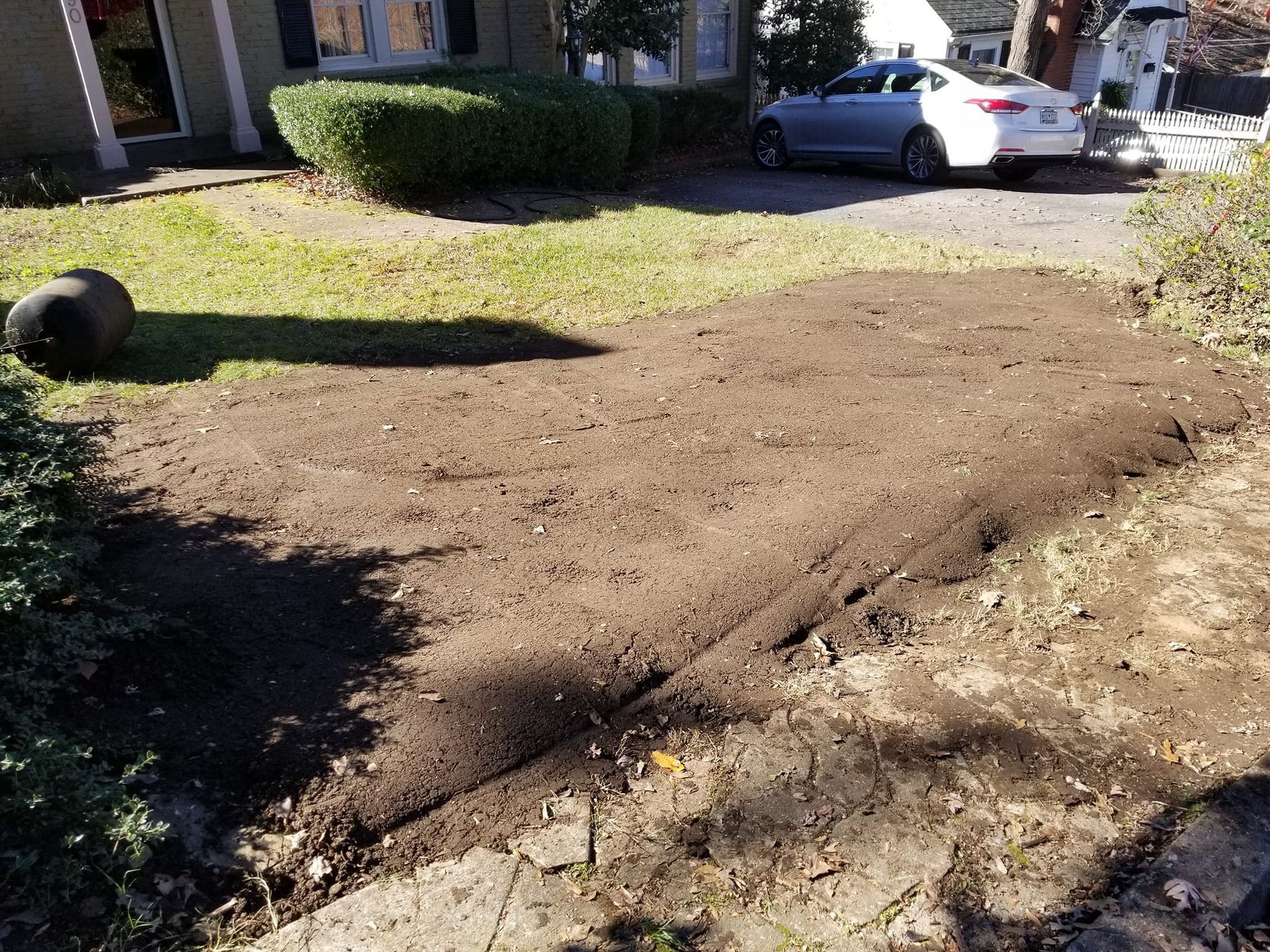 A car is parked in a driveway next to a pile of dirt. inman