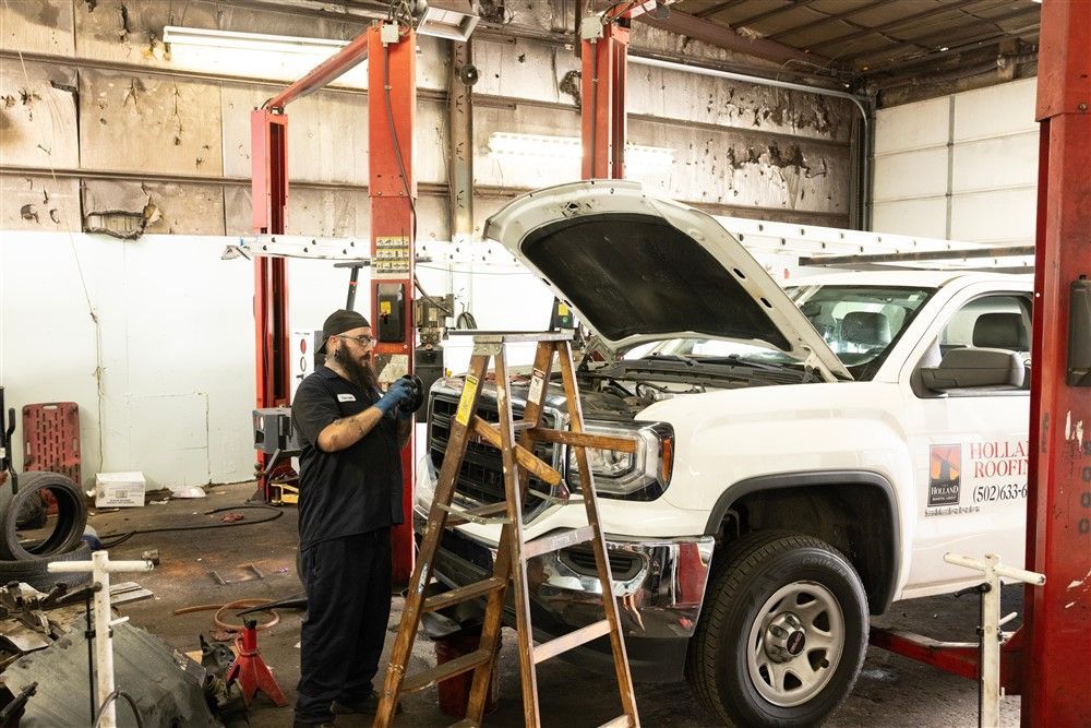 A man is working on the underside of a truck with a wrench.