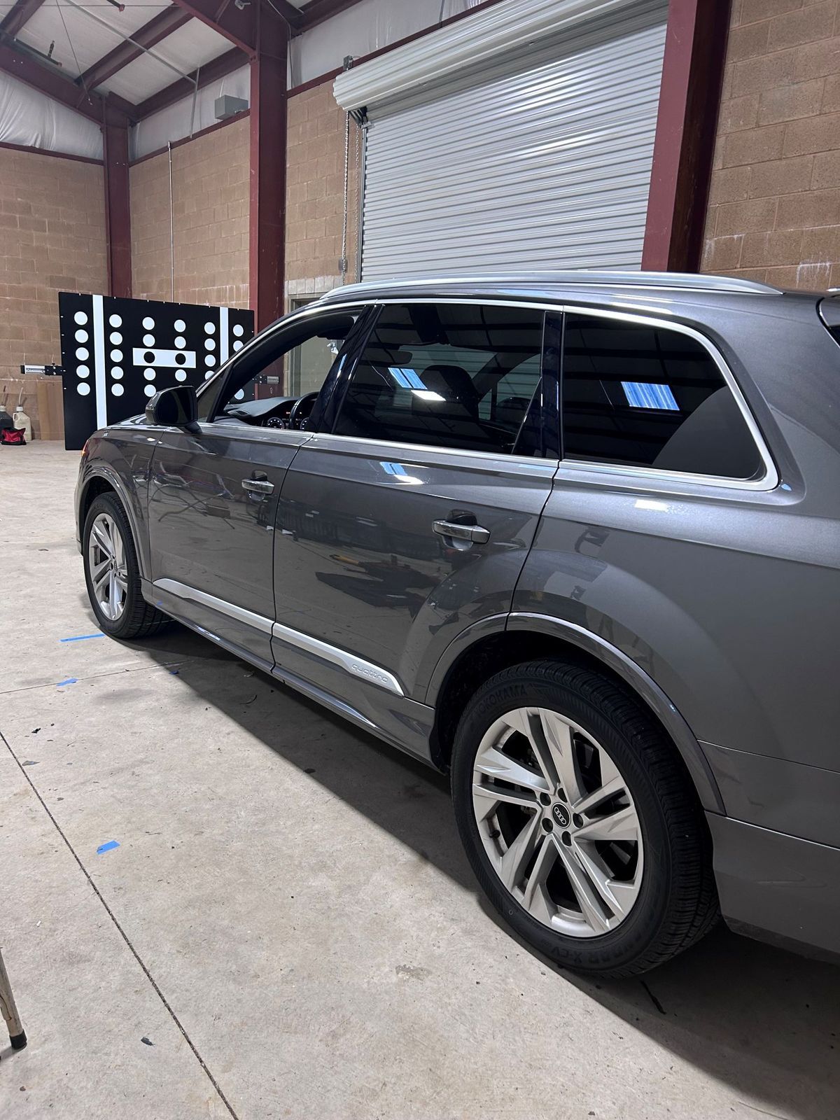 Silver SUV parked inside a warehouse garage with a roll-up door and concrete floor