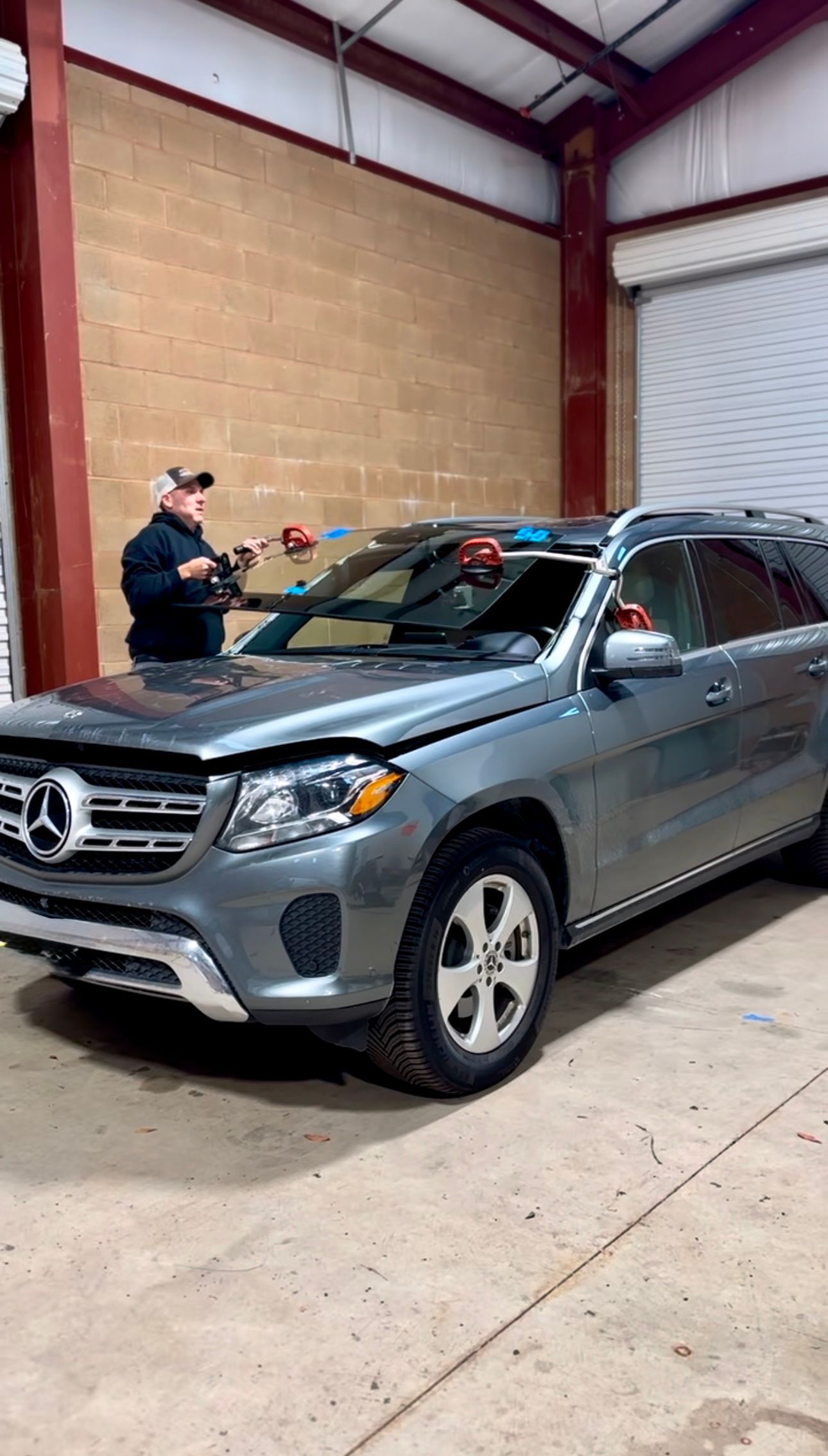 Silver Mercedes SUV in a warehouse, with a person standing beside the driver’s side window.
