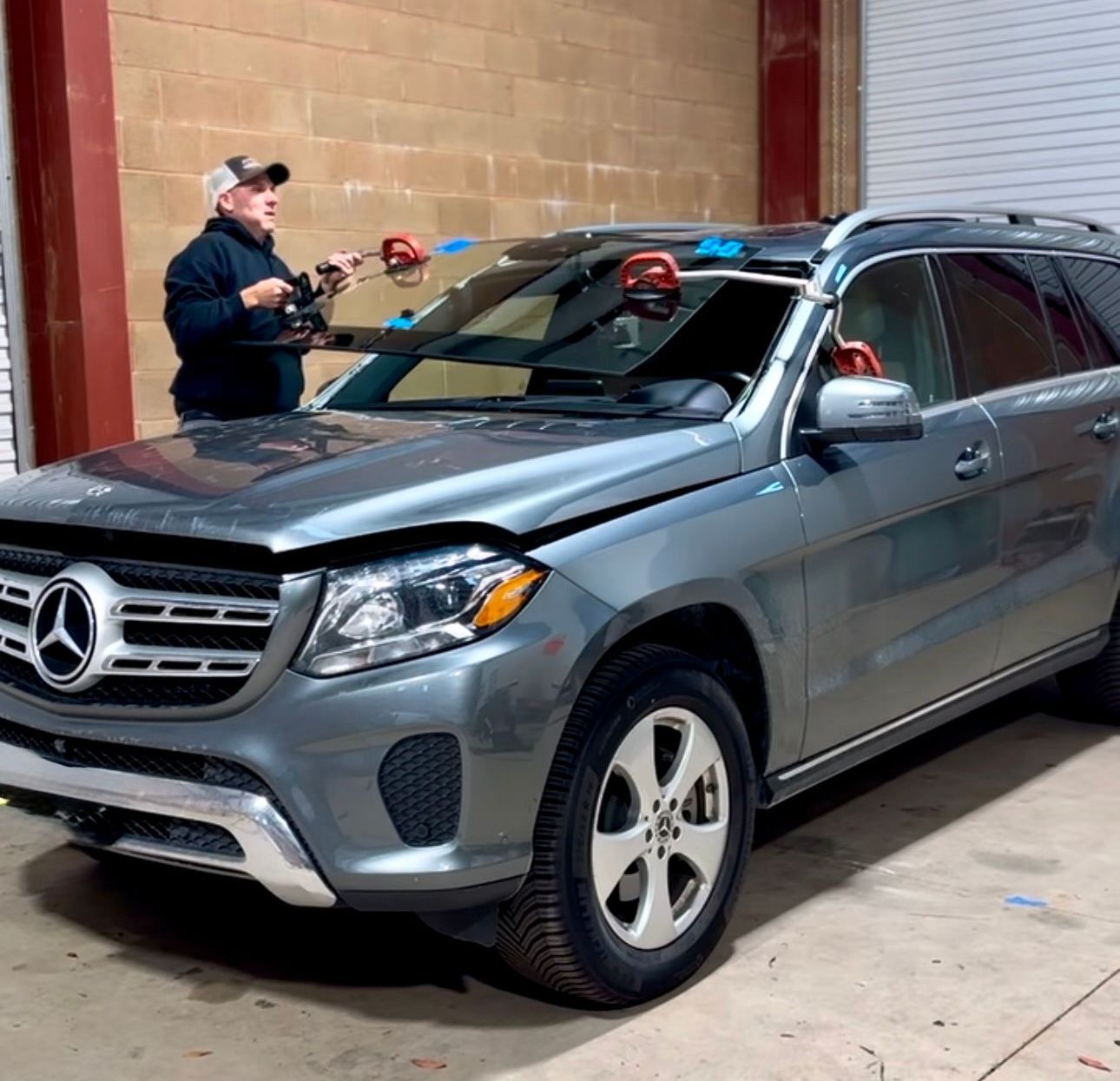 Windshield replacement in Grass Valley, CA Gray Mercedes SUV in a warehouse, with a person standing beside it near the windshield.