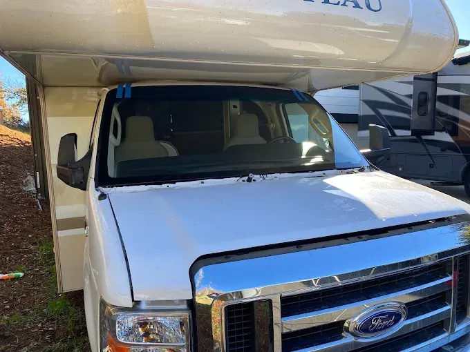 Ford ADAS Calibration in Truckee, CA White utility truck parked under a camper, front view with chrome grille and windshield in shade