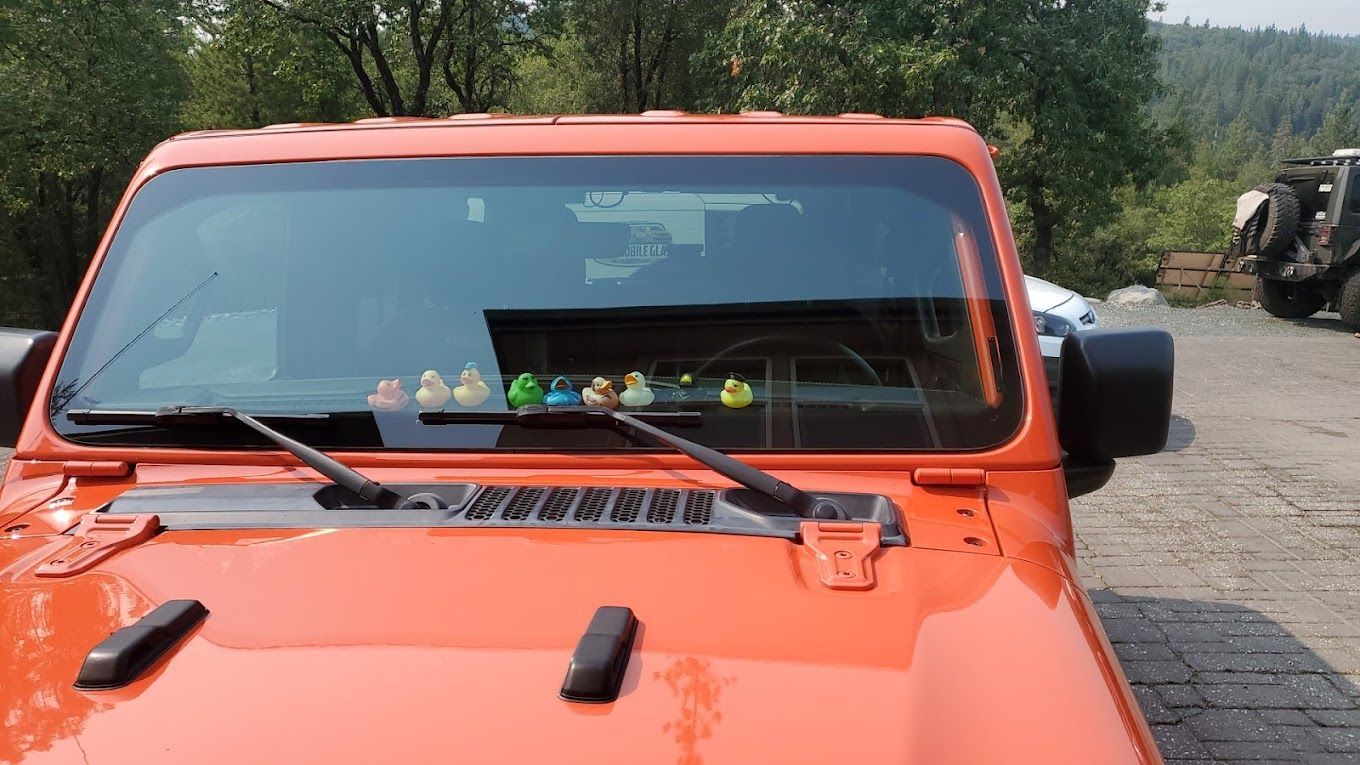Orange off-road vehicle front parked outdoors with a wooded background and gravel road