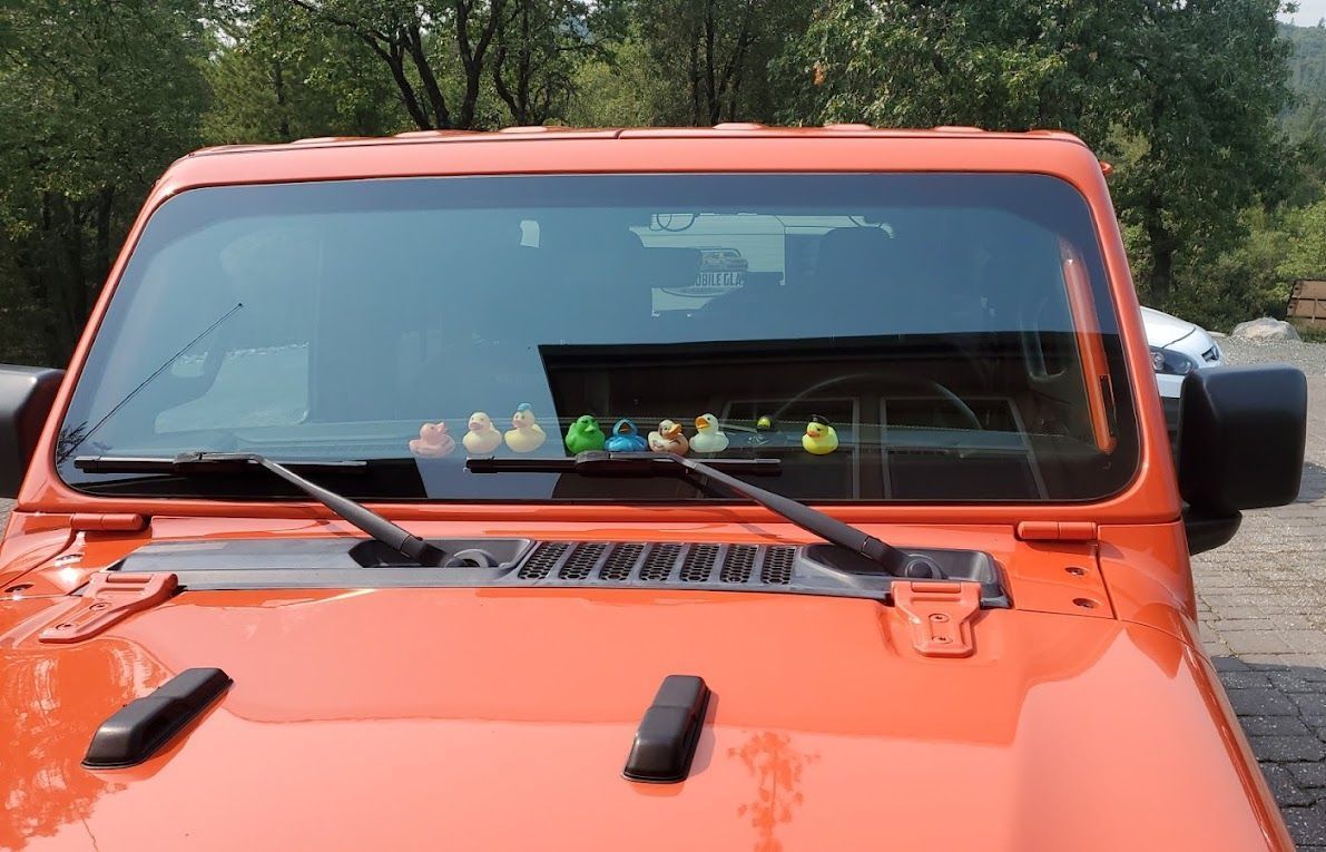 Orange off-road truck front view with windshield wipers and dashboard ornaments, parked outdoors.