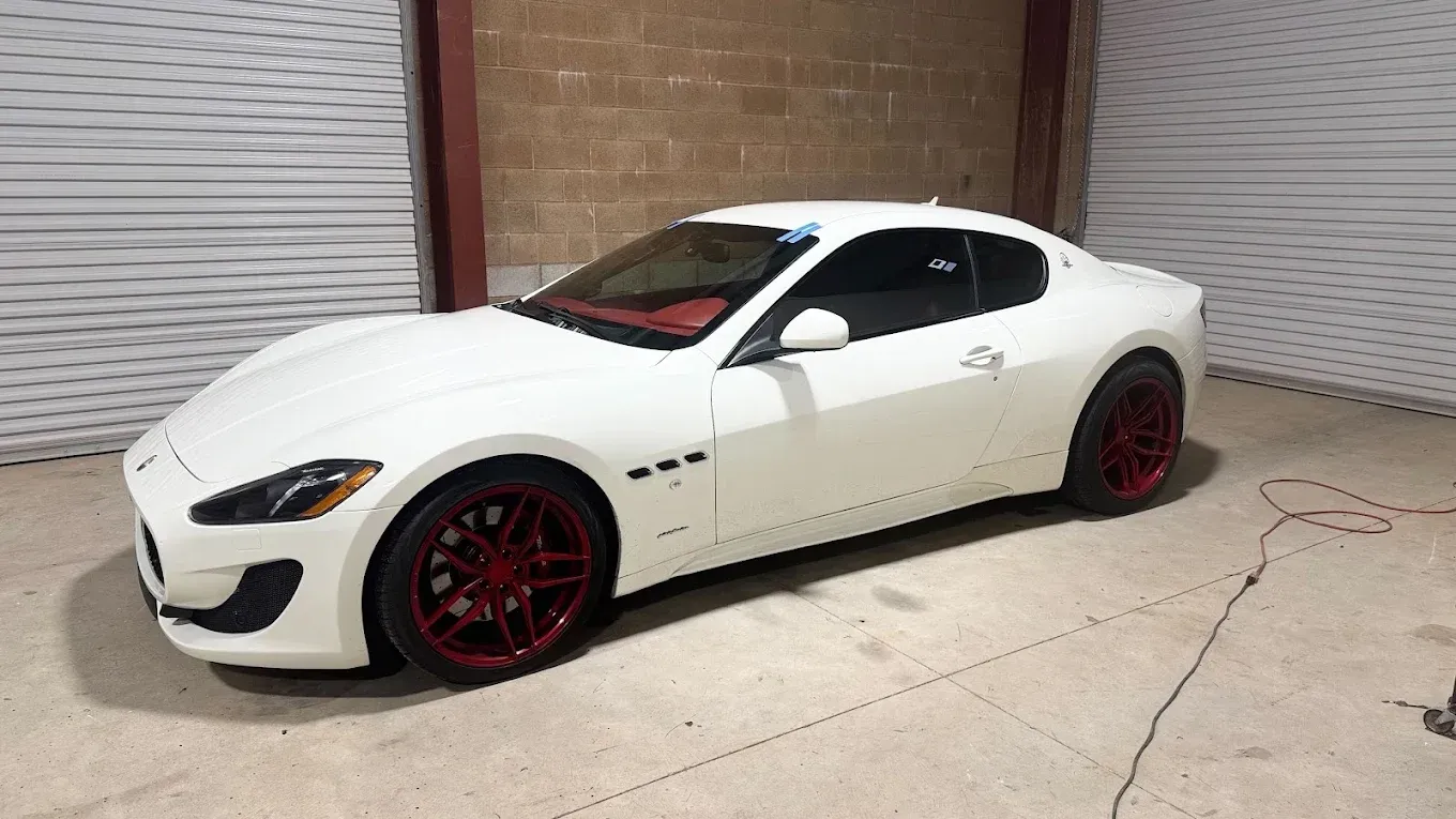 Certified auto glass replacement services in Truckee, CA White sports coupe with red rims parked in front of closed garage doors