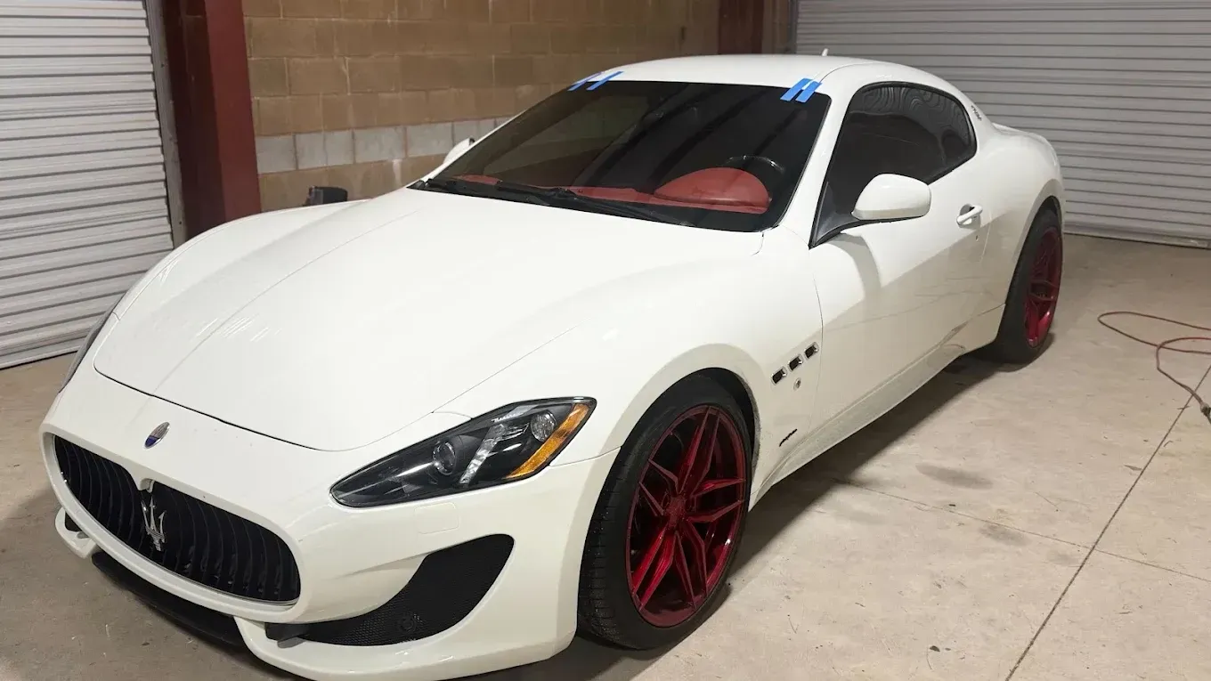 White sports car with red rims parked in a garage or driveway
