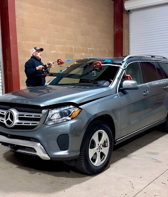 Mercedes windshield replacement in Grass Valley, CA Gray Mercedes SUV in a garage while a worker uses a measuring tool on the windshield