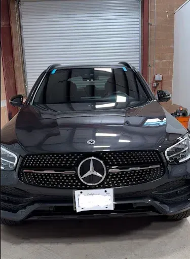 Black Mercedes-Benz SUV parked indoors in front of a closed metal garage door.