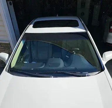 White sedan parked in a garage, viewed from above through the windshield.