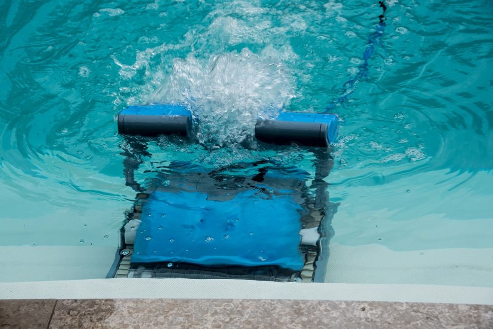 A Robotic Pool Cleaner Is Cleaning A Swimming Pool — Col Davies Pools In Warners Bay, NSW