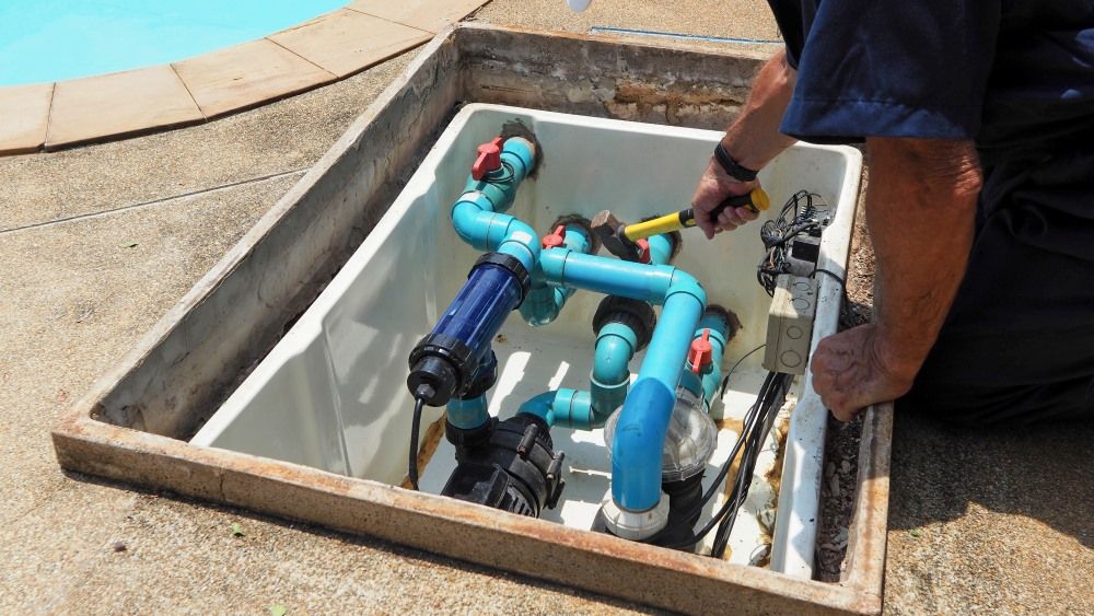 A Man Is Working On A Swimming Pool Pump — Col Davies Pools In Port Stephens, NSW