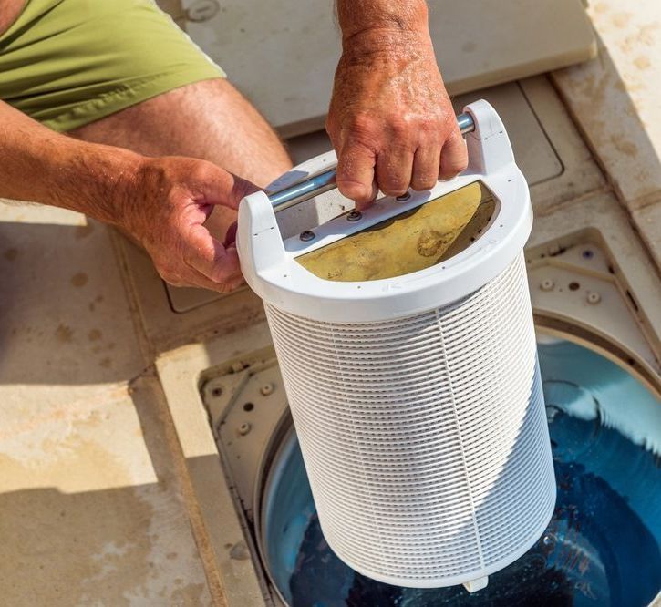 A Man Is Cleaning A Pool Filter In A Swimming Pool — Col Davies Pools In Maitland, NSW