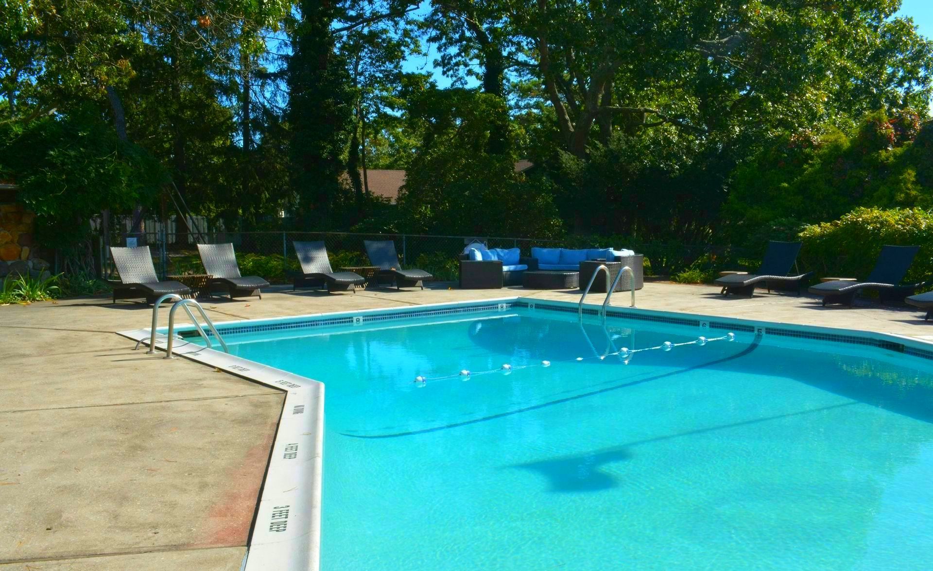 A large swimming pool is surrounded by chairs and trees — Col Davies Pools In Warners Bay, NSW