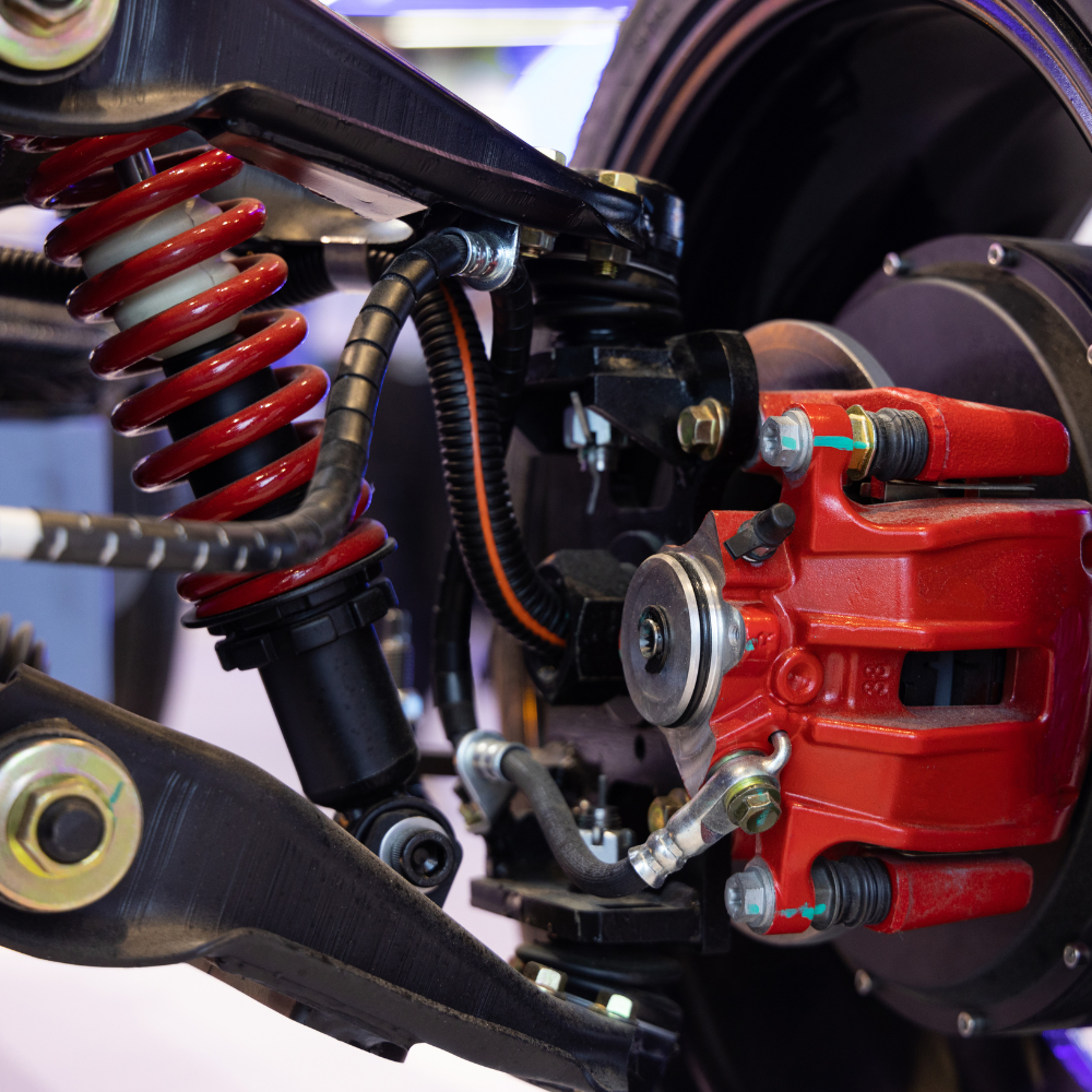 Close-up of a car suspension and red brake caliper assembly with coil spring and wheel hub