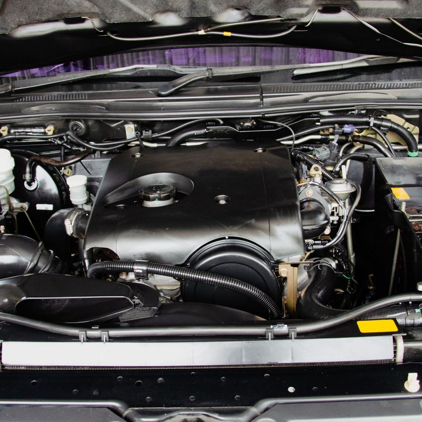 Close-up of a car engine bay with a large black intake cover and visible hoses and wiring