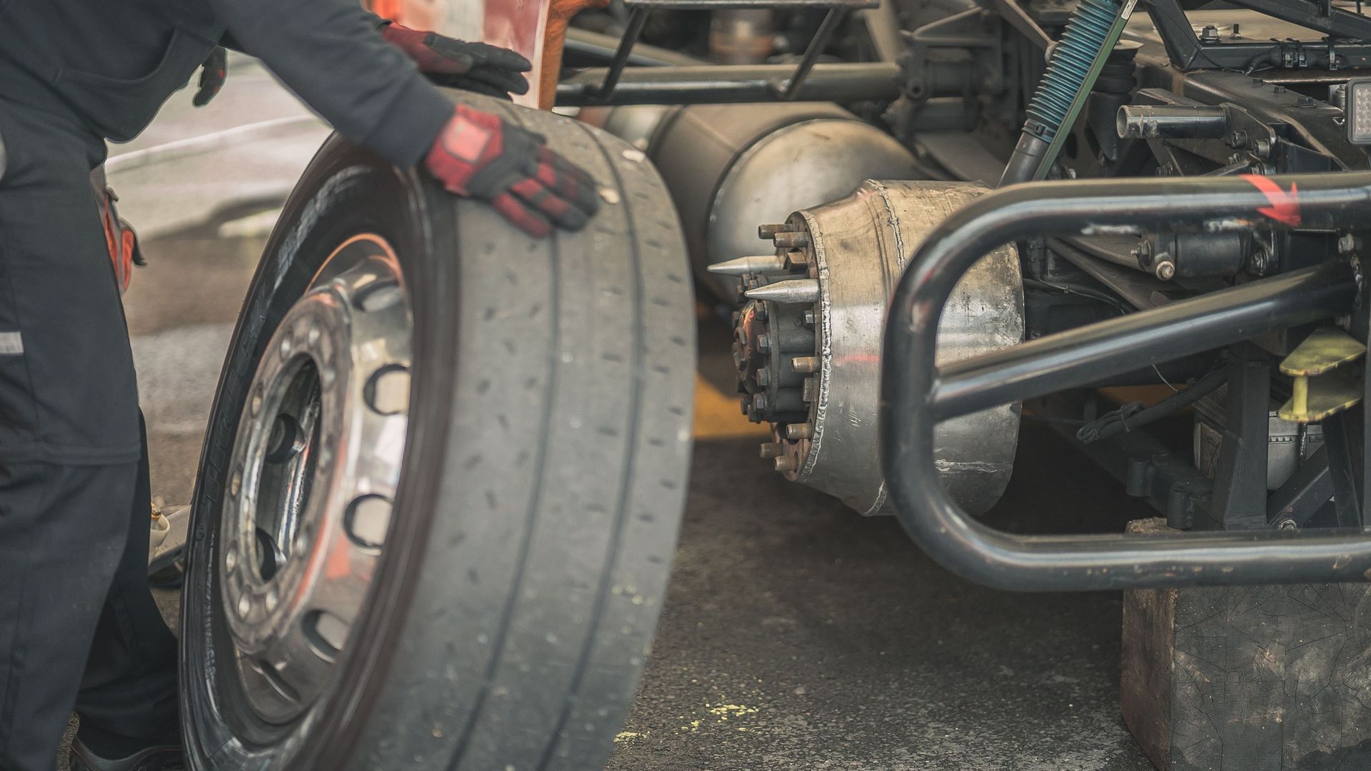 Formula car wheel being removed by a mechanic in black gloves during a pit stop