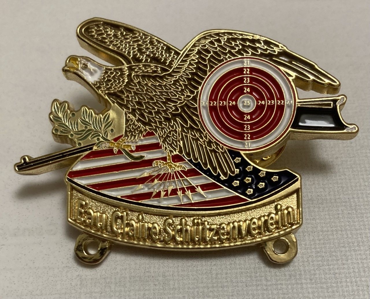 A gold pin with an eagle and a target on it