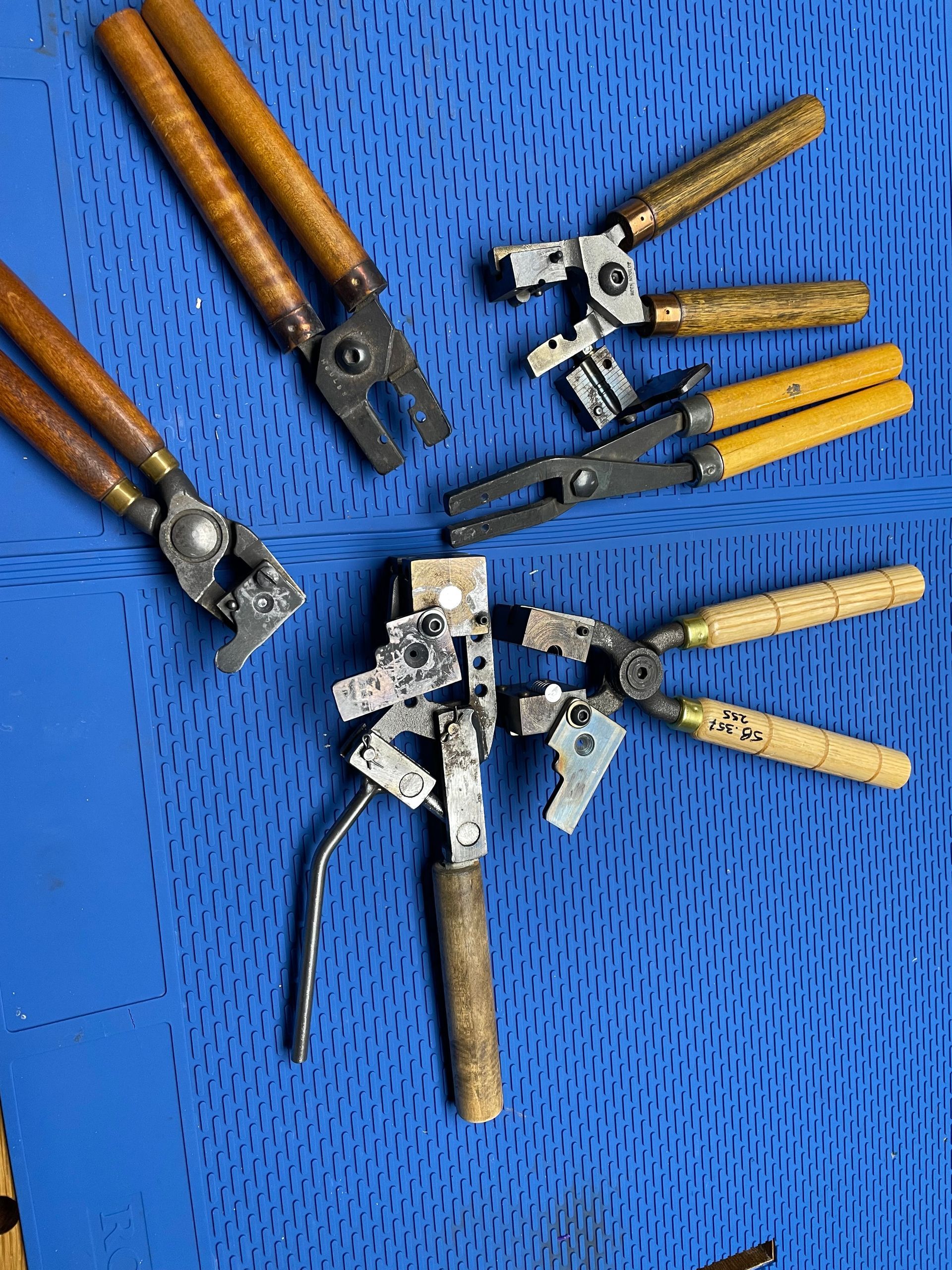 A bunch of pliers are sitting on top of a blue mat.