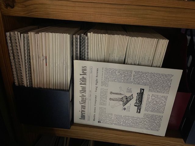 A stack of books on a shelf with a newspaper on top