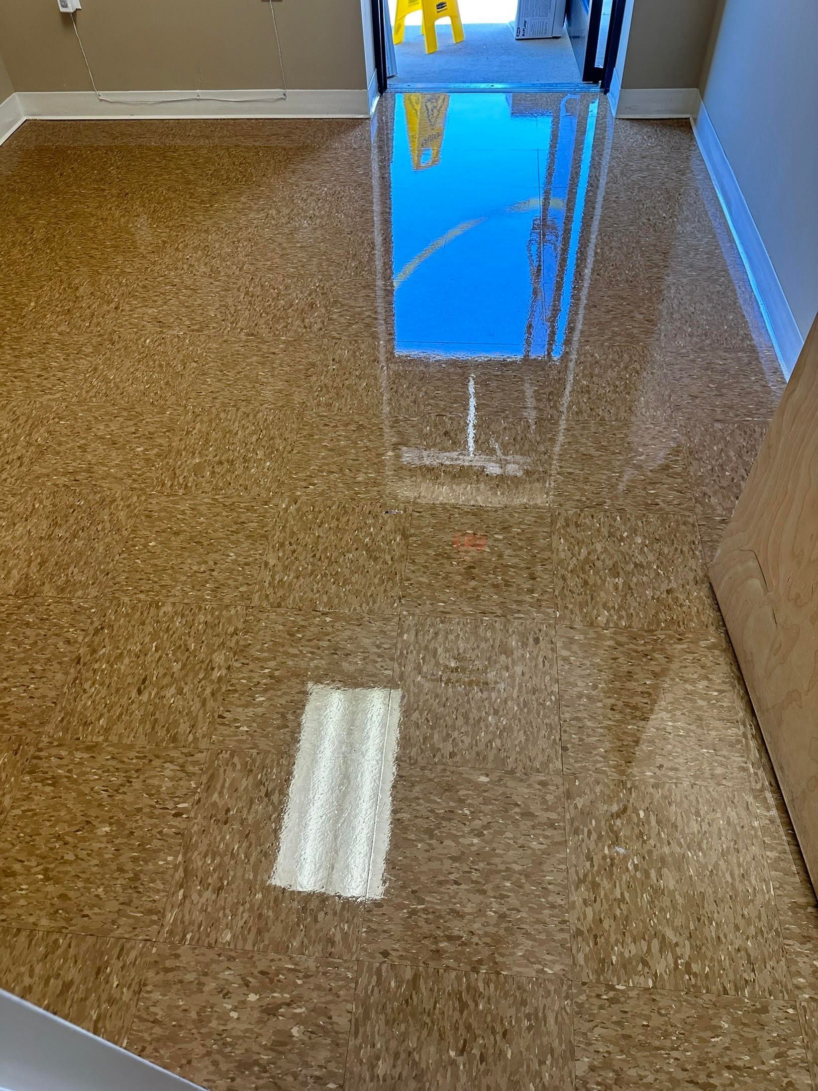 Brown speckled flooring reflecting a blue object and overhead lights.