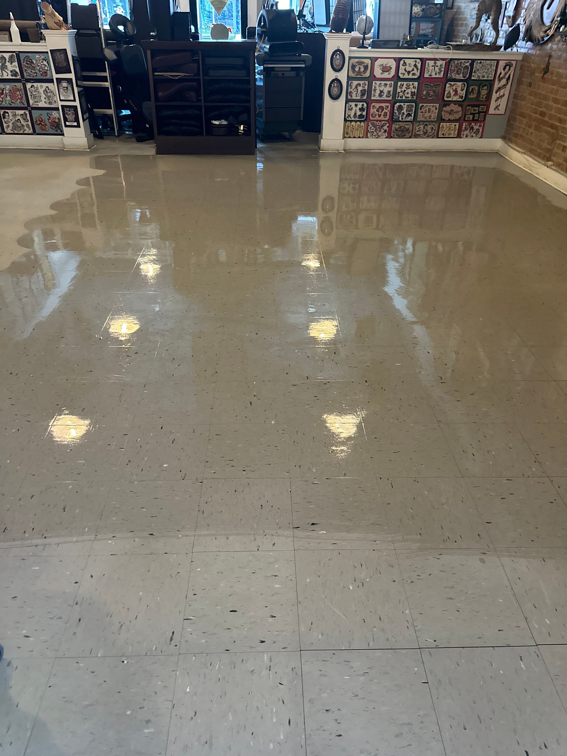 Shiny, light gray concrete floor reflecting overhead lights in a store with shelves and products.