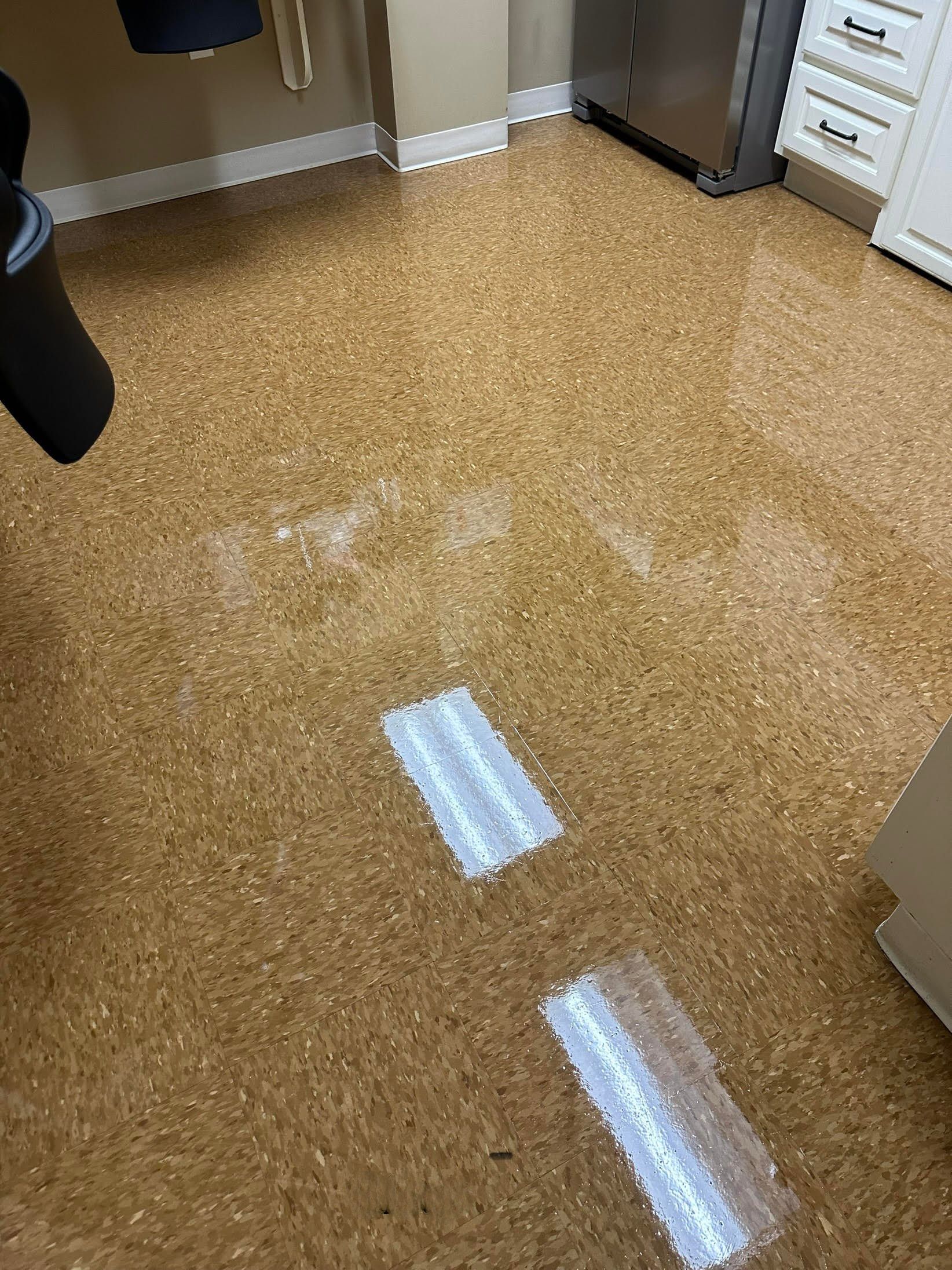 Brown cork flooring with two white rectangles, likely tape. Bright light reflects off the surface.
