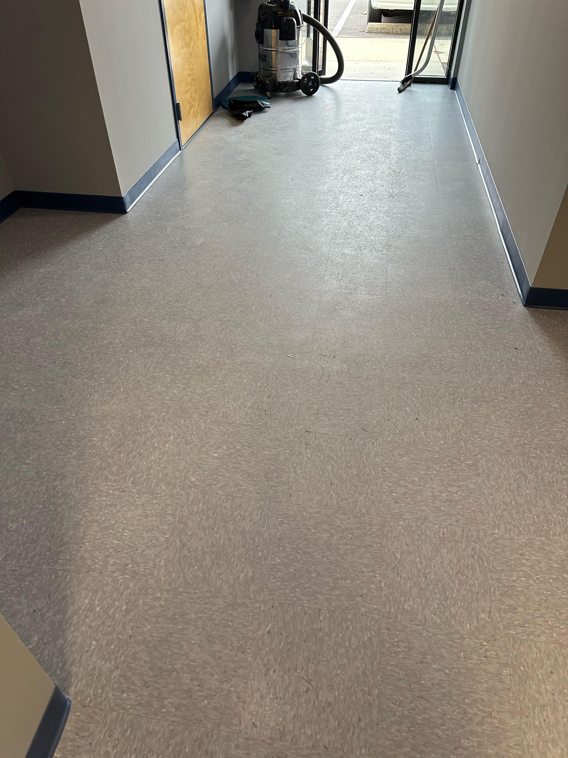 Gray flecked epoxy floor in a hallway with gray walls and a doorway.