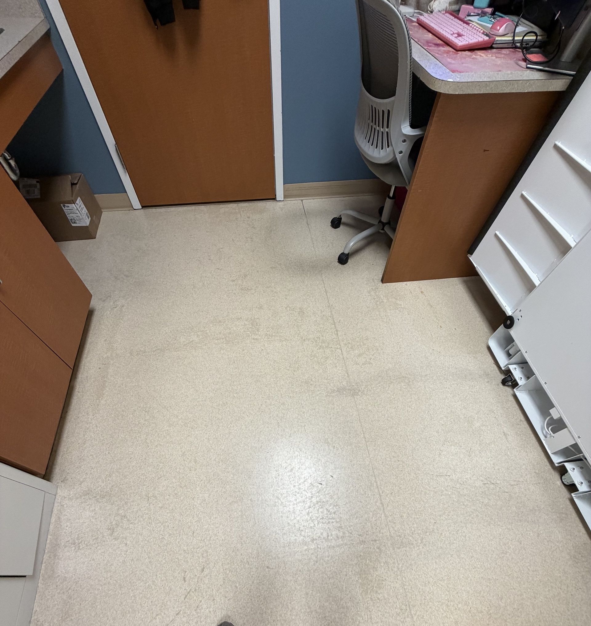 Black rectangular doormat in front of a white door on a wooden floor.