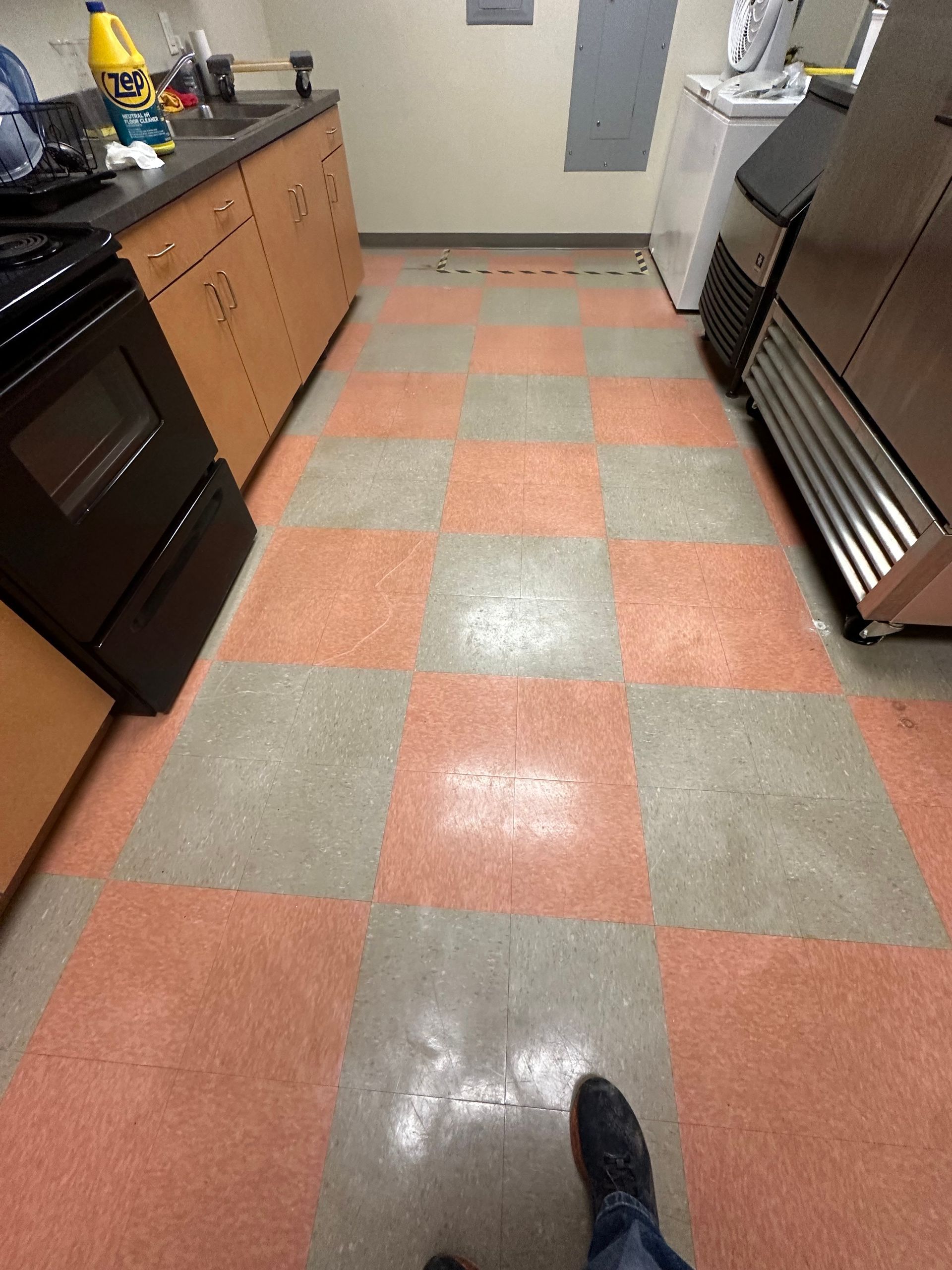 Red and gray checkerboard kitchen floor with black appliances and cabinets.