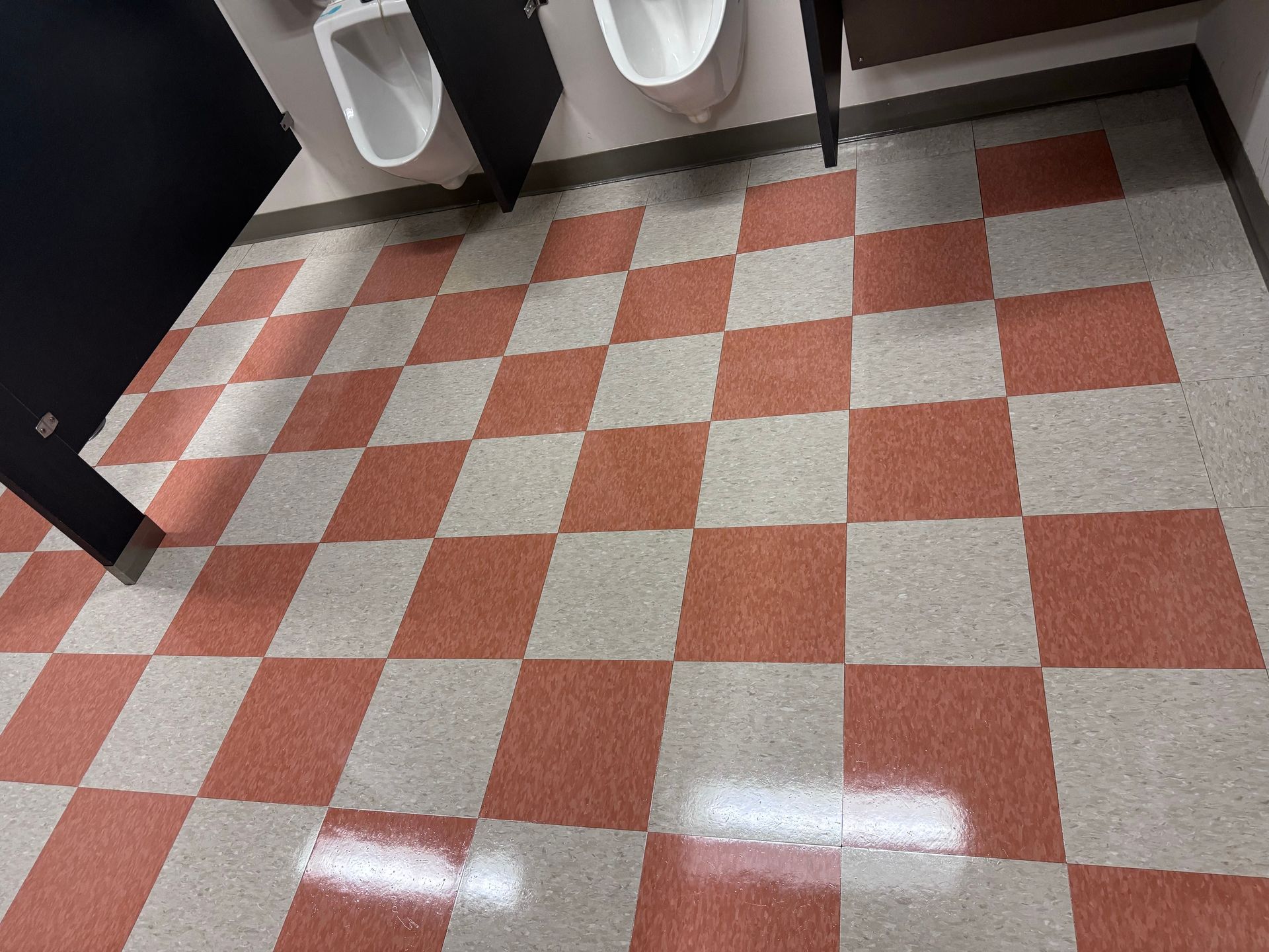 Red and white checkered tile floor in a public restroom with urinals.