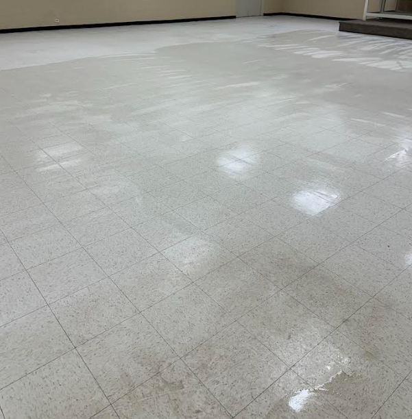 Wet, light-colored tile floor reflecting light, in an empty room.